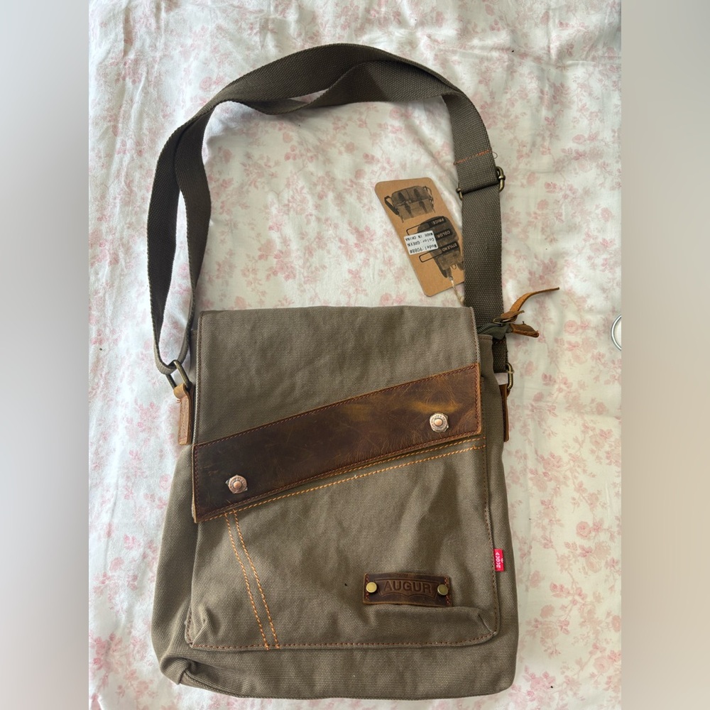 Brown canvas Augur messenger bag with leather details and multiple pockets. NWT